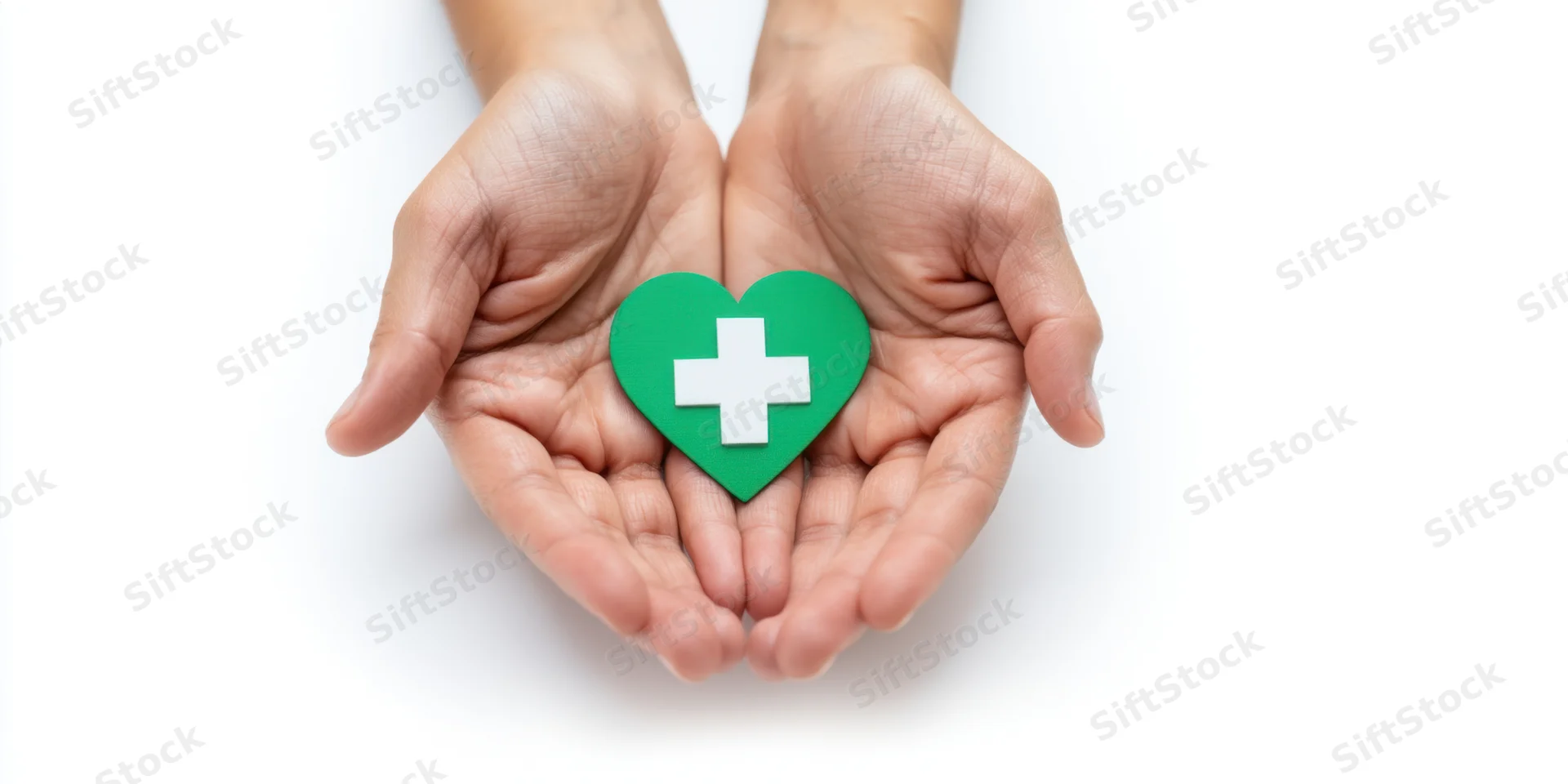 Cupped hands holding a green heart with white cross symbol against white background