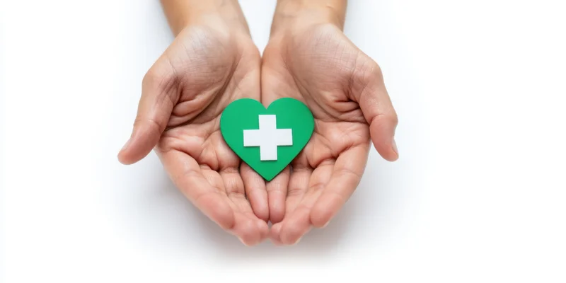 Cupped hands holding a green heart with white cross symbol against white background