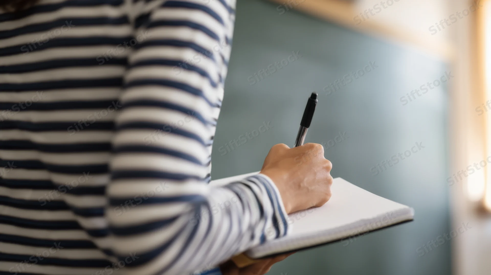 Woman writing in notebook in classroom setting
