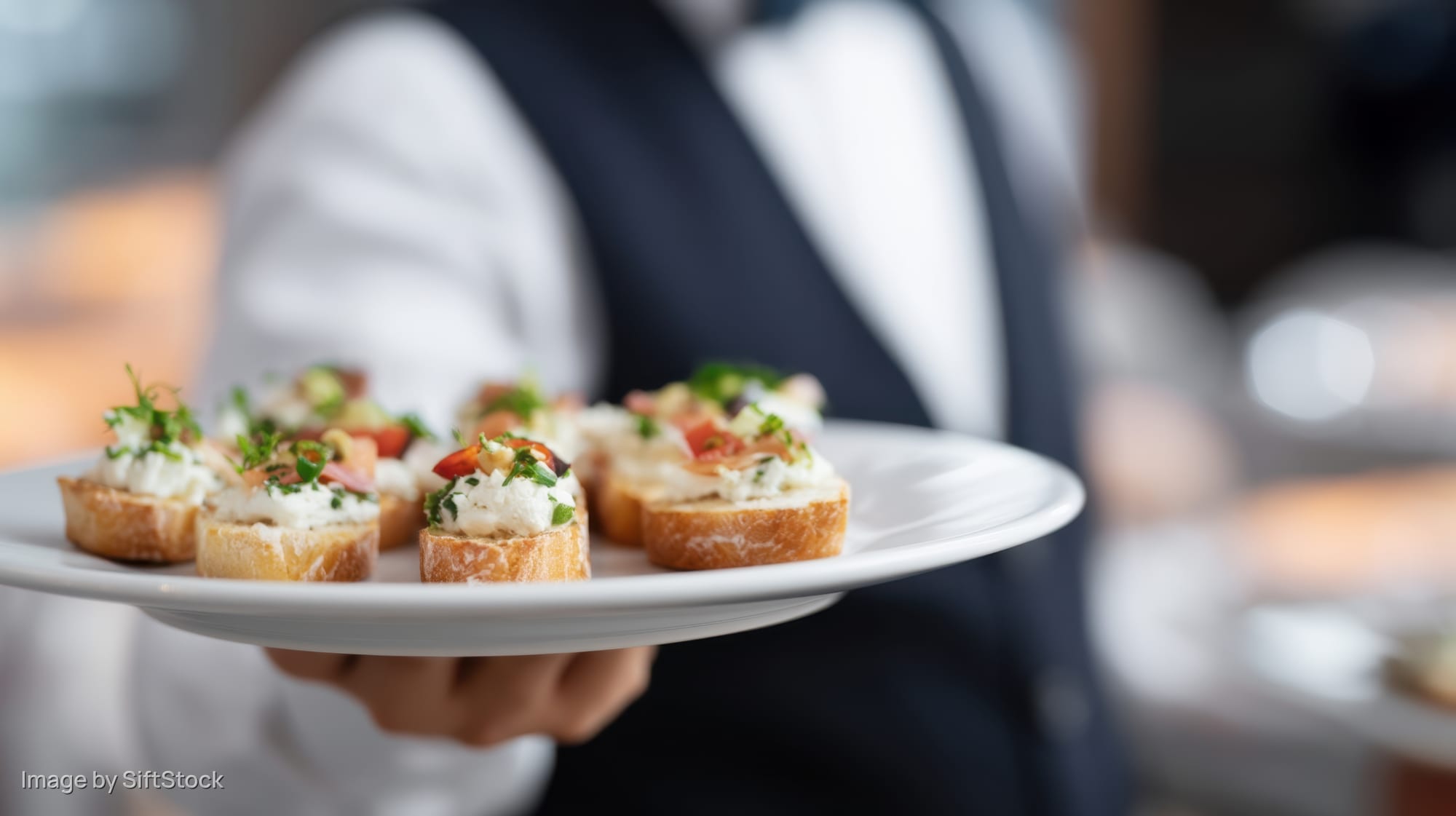 Waiter holding a plate of appetizers in a restaurant setting