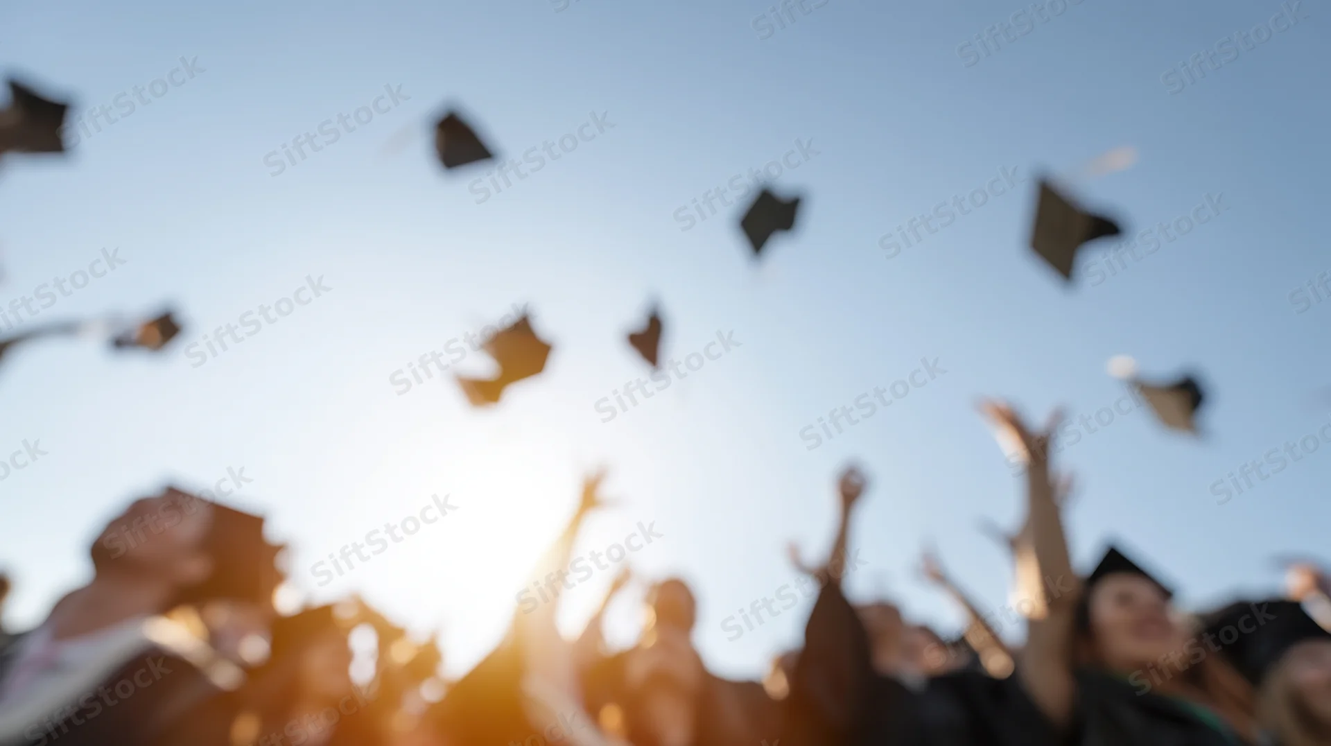 Graduates throwing caps into the sky during outdoor ceremony