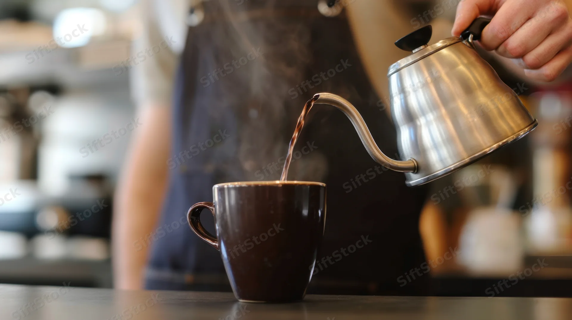 Barista pouring hot coffee from a gooseneck kettle into a ceramic mug on a cafe countertop