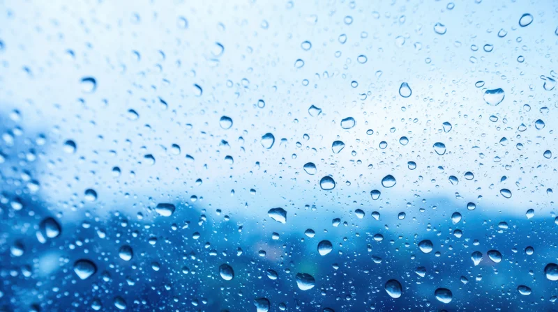 Raindrops on a glass surface with blurred blue background