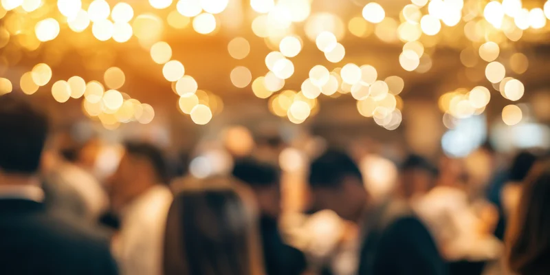 Blurred crowd at an indoor reception under warm string lights