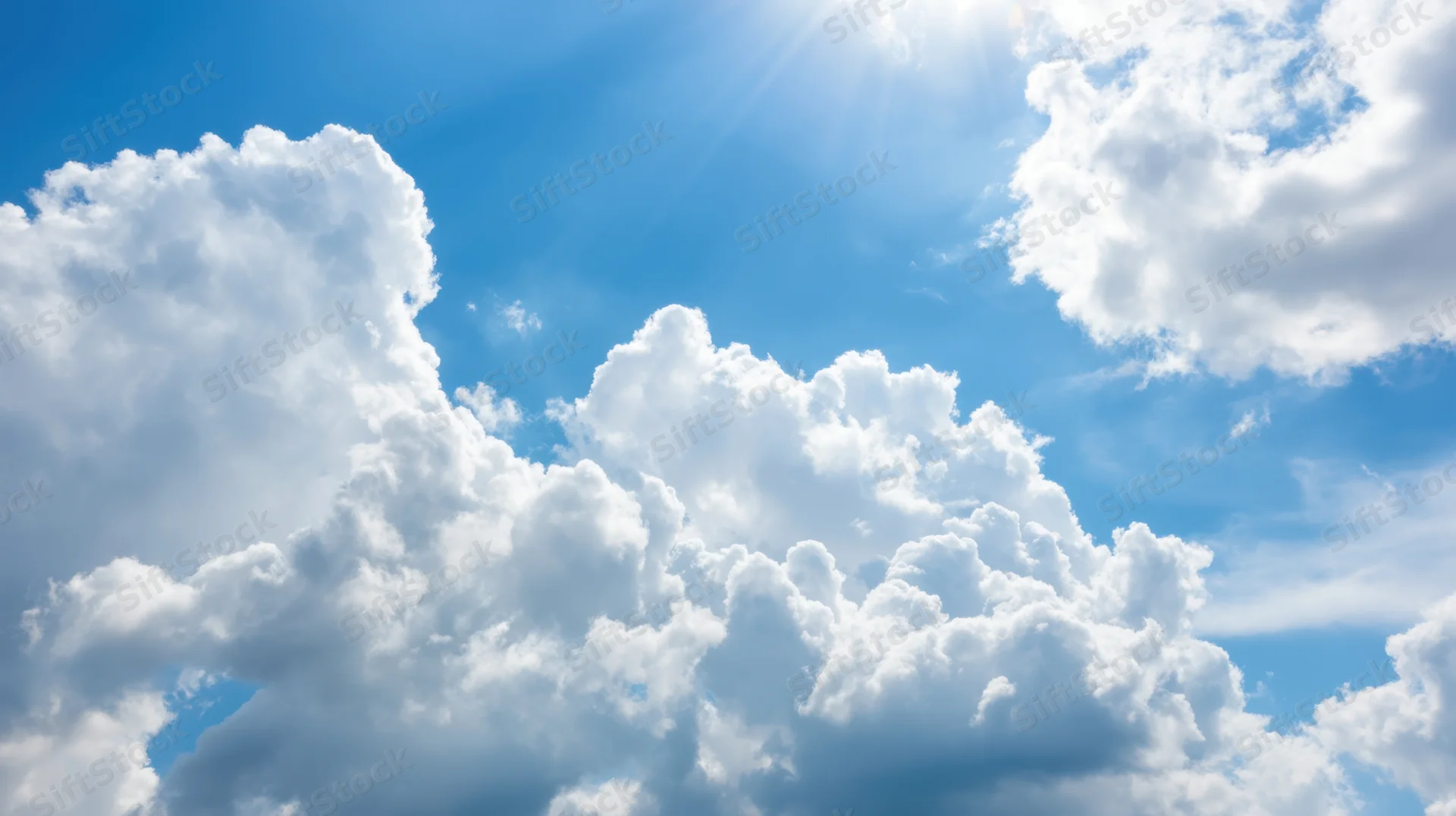 Bright blue sky filled with fluffy white cumulus clouds and sunbeams