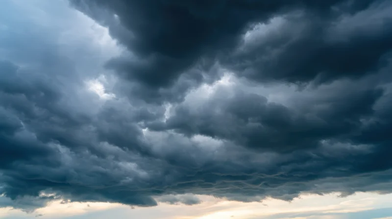 Dramatic stormy sky with dark clouds and light breaking through at horizon