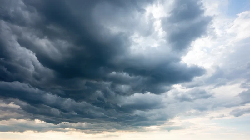 Dramatic stormy sky with dark clouds and sunlight breaking through at horizon