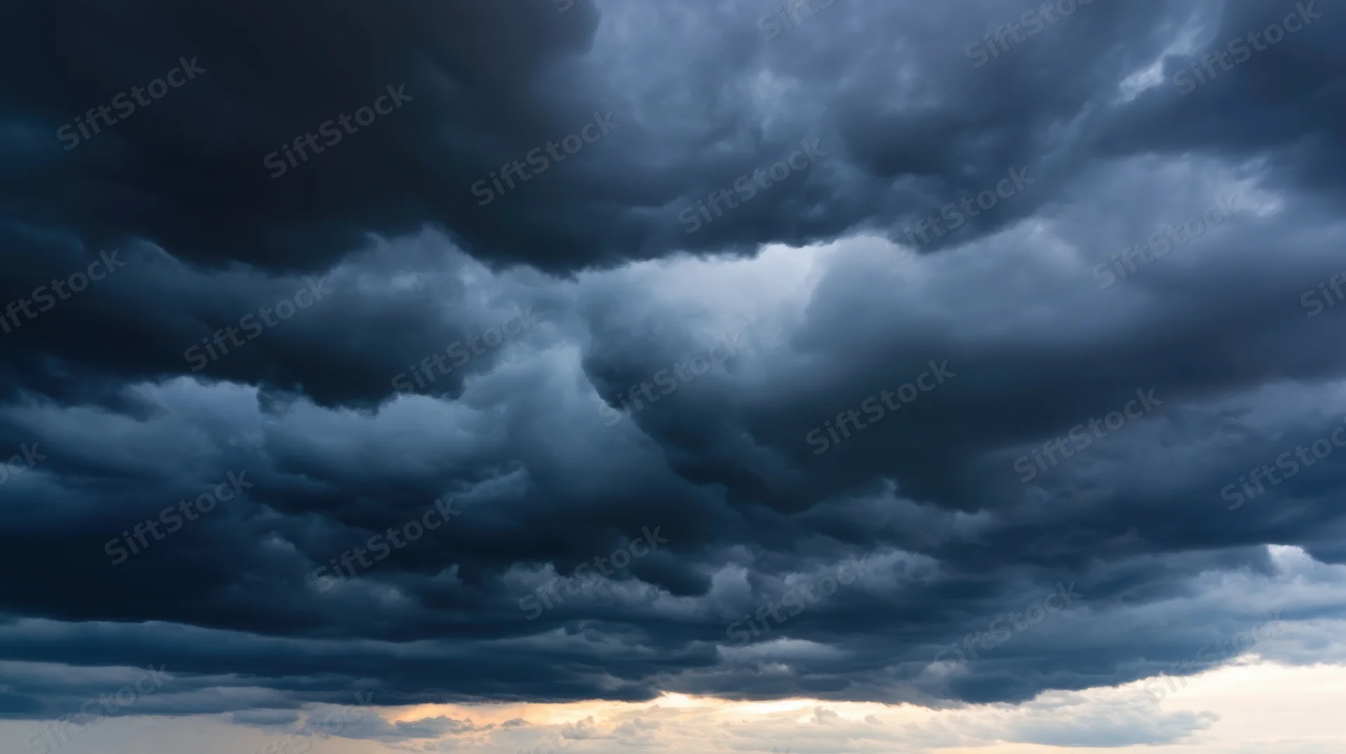Dark storm clouds filling the sky with a hint of light at the horizon