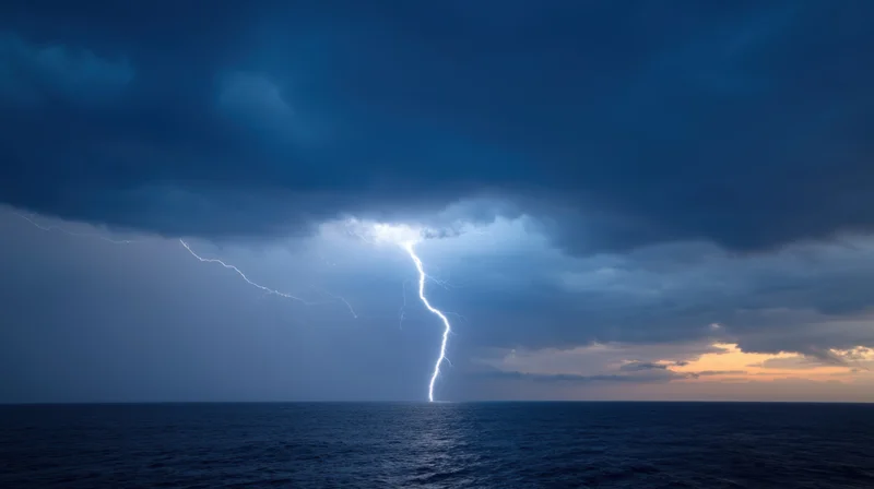 Lightning striking the ocean under dark storm clouds at dusk