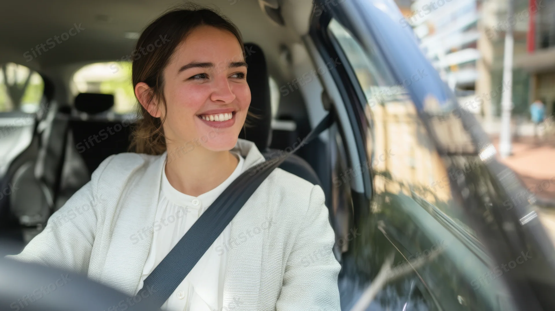 Smiling woman driving a car in an urban setting