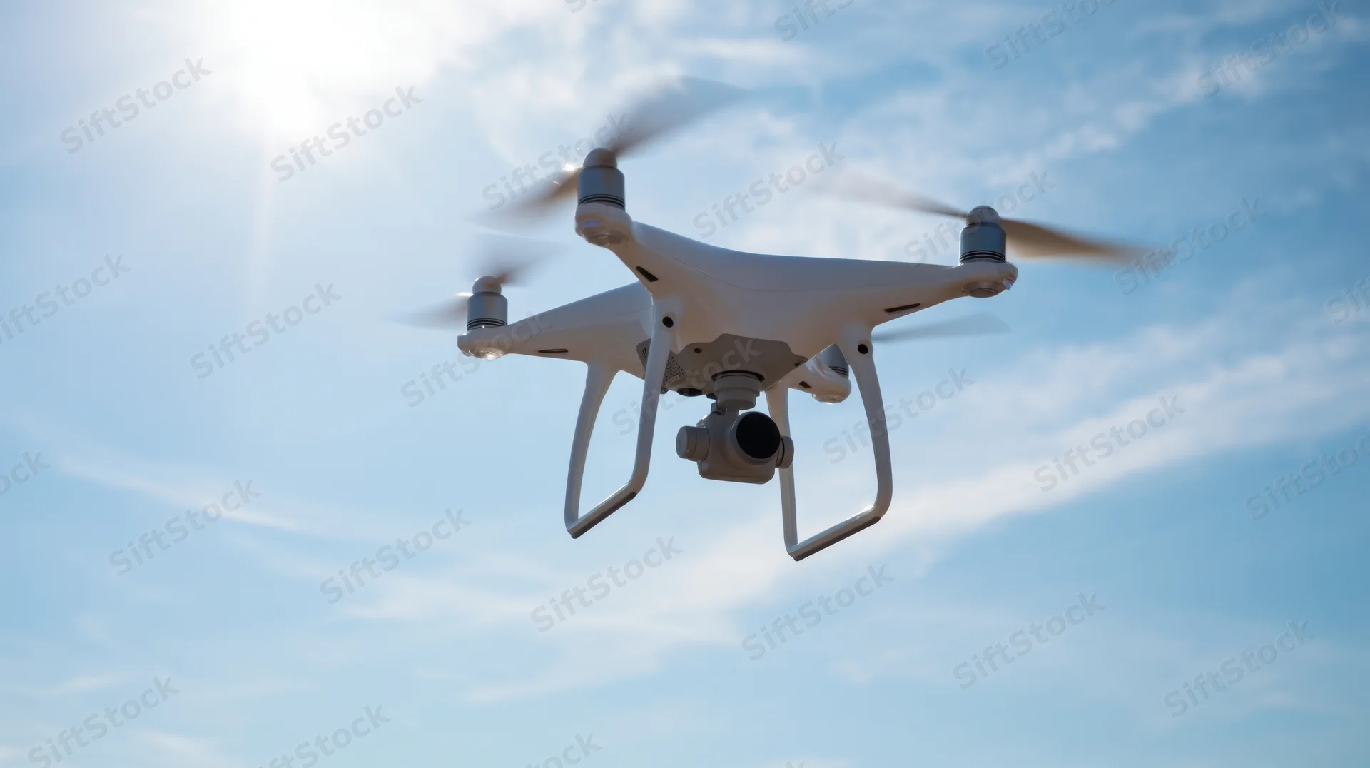 White quadcopter drone flying in the sky with camera and spinning propellers