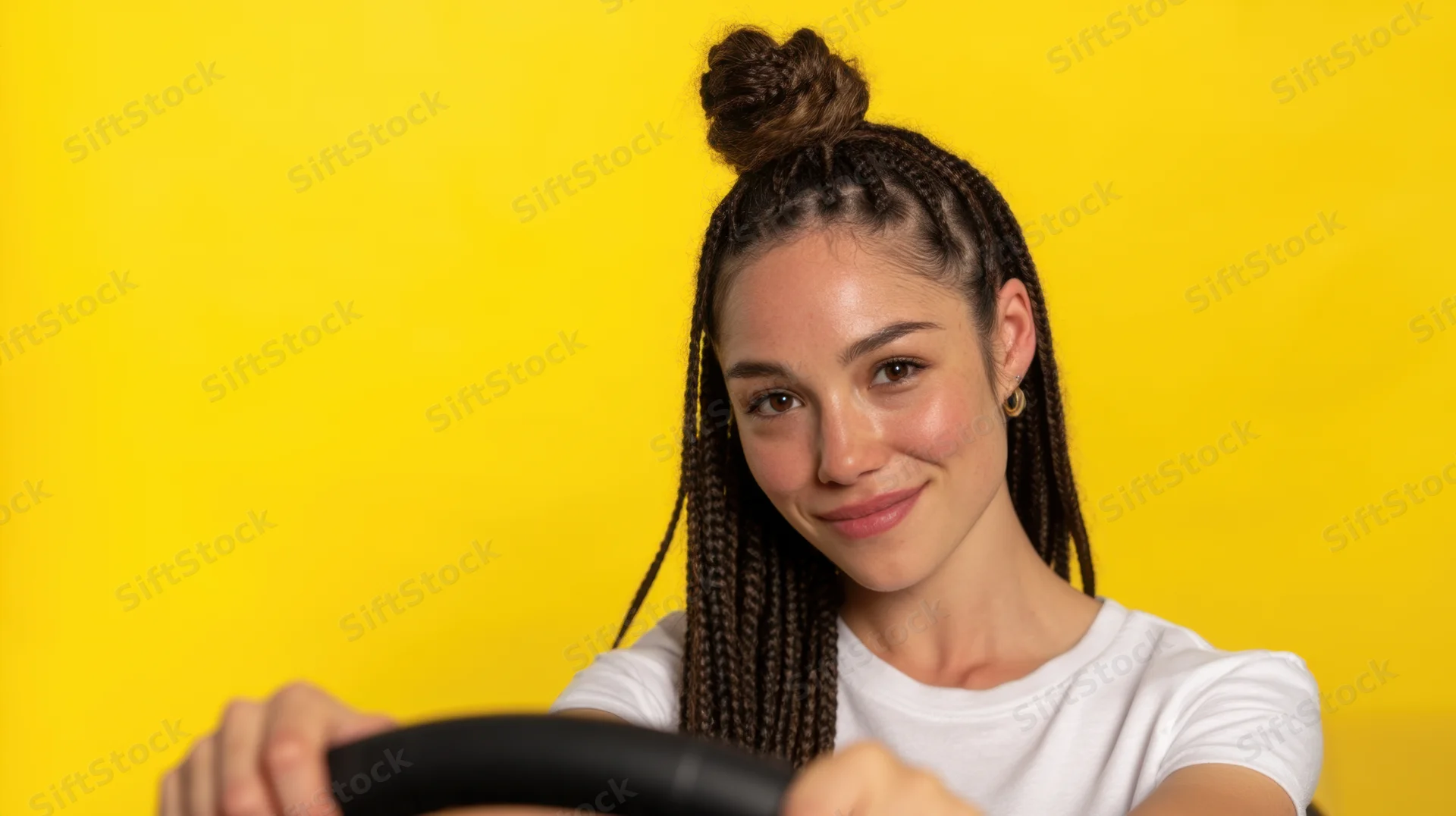 Young woman smiling while holding steering wheel against yellow background