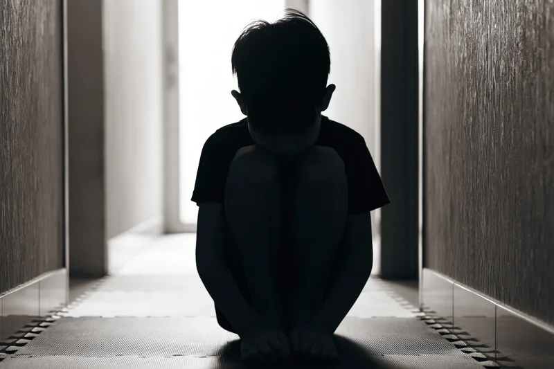 Child sitting in silhouette on foam puzzle mat in narrow hallway