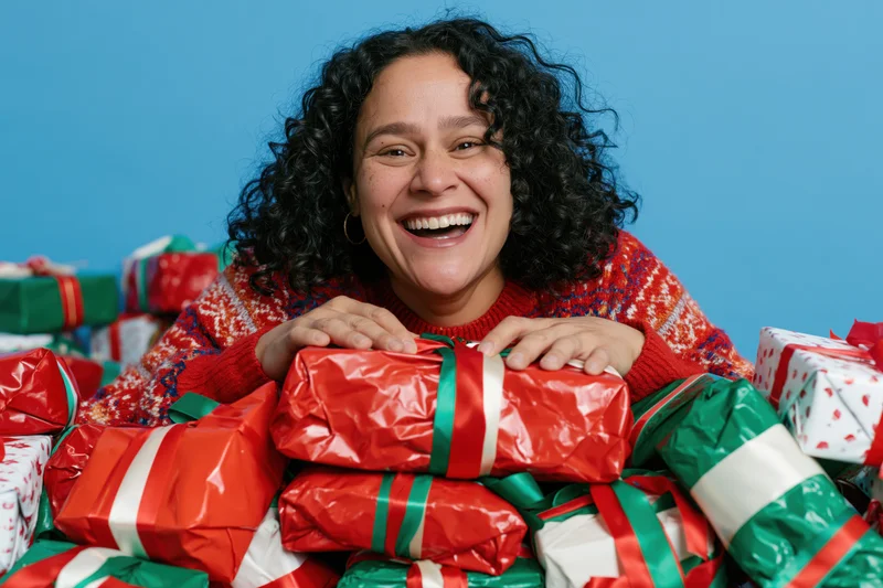 Woman smiling with wrapped gifts in a studio setting