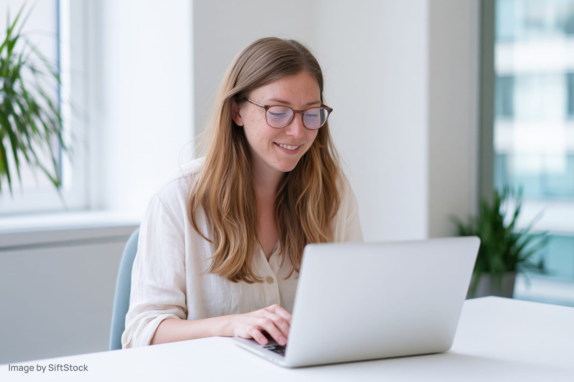 Woman smiling while typing on laptop at office desk
