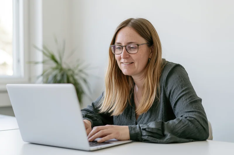 Woman working on laptop at desk in bright office space