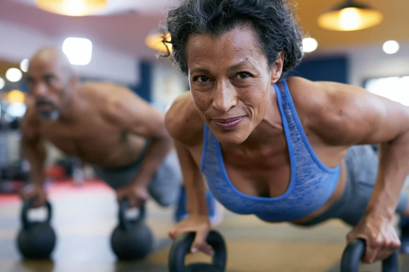 Woman doing push-ups with kettlebells in a gym