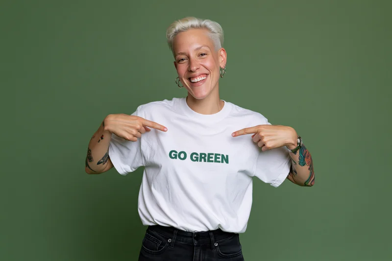 Woman smiling and pointing at go green text on white tshirt against green background