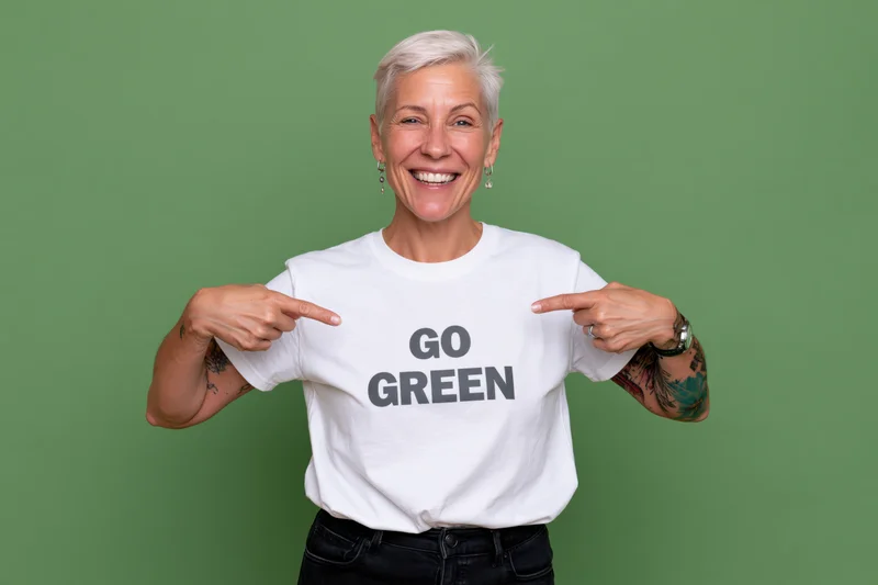Smiling woman pointing at go green text on her tshirt in studio