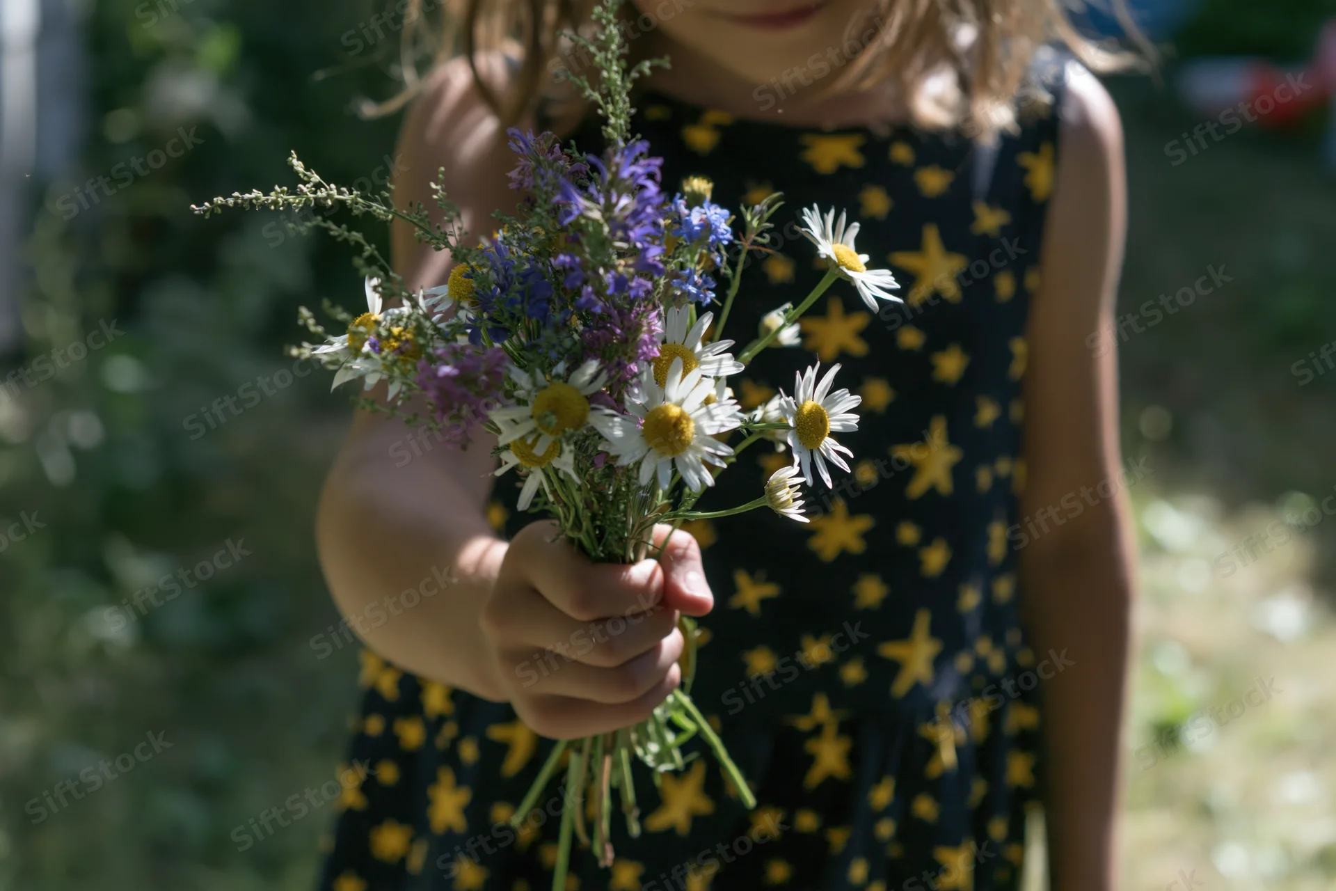 Girl holding a bouquet of wildflowers in a garden on a sunny day