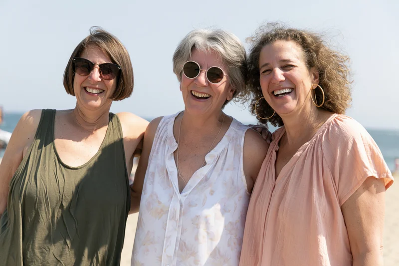 Three women smiling together on a sunny beach