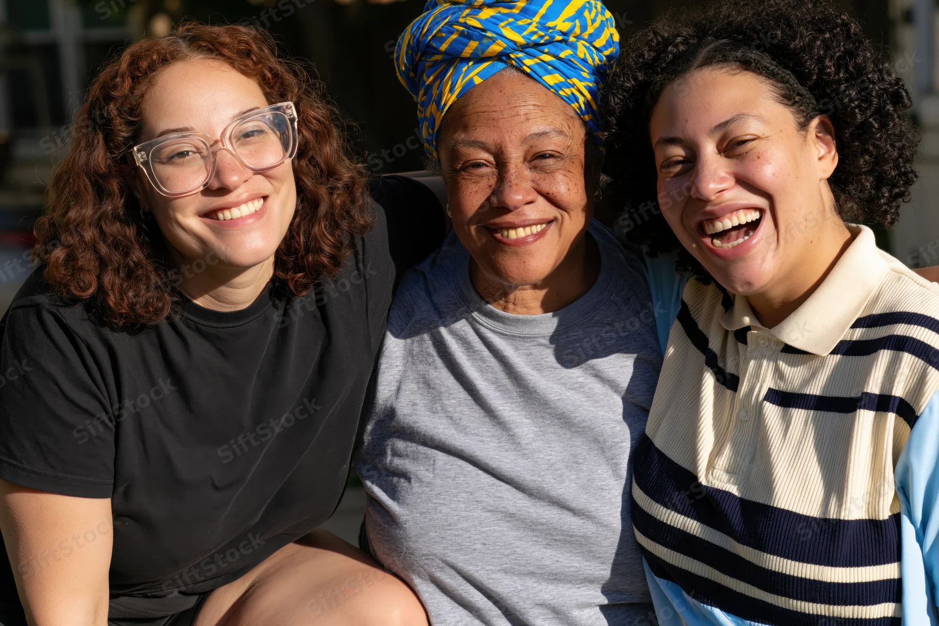 Three women smiling and laughing together outdoors in a close group portrait